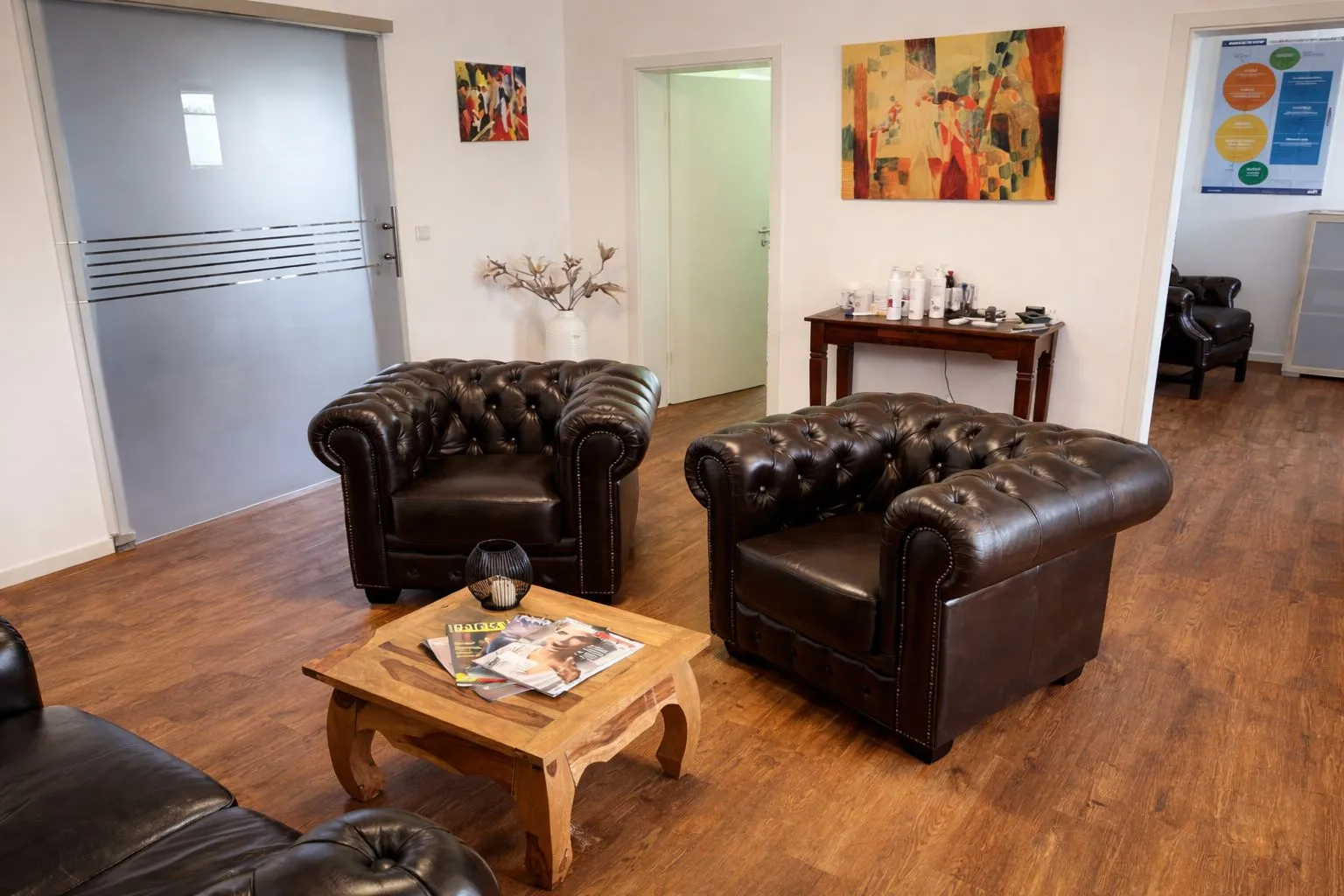 Ralf Baumhöfer – Psychotherapiepraxis – Dieses Bild zeigt klassische dunkelbraune Chesterfield-Sessel aus Leder mit ihrer charakteristischen tiefen Knopfheftung und den geschwungenen Armlehnen.